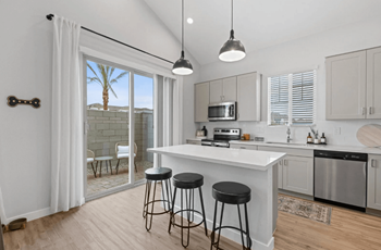 A kitchen with a white counter and black stools.